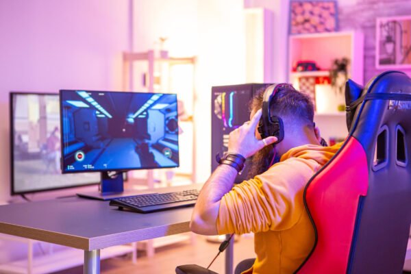 bearded man playing online video games his pc talking with others players colorful neons room