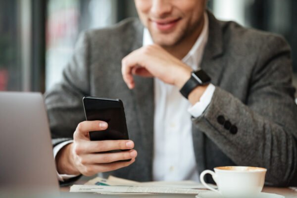 cropped image happy businessman sitting by table cafe using smartphone