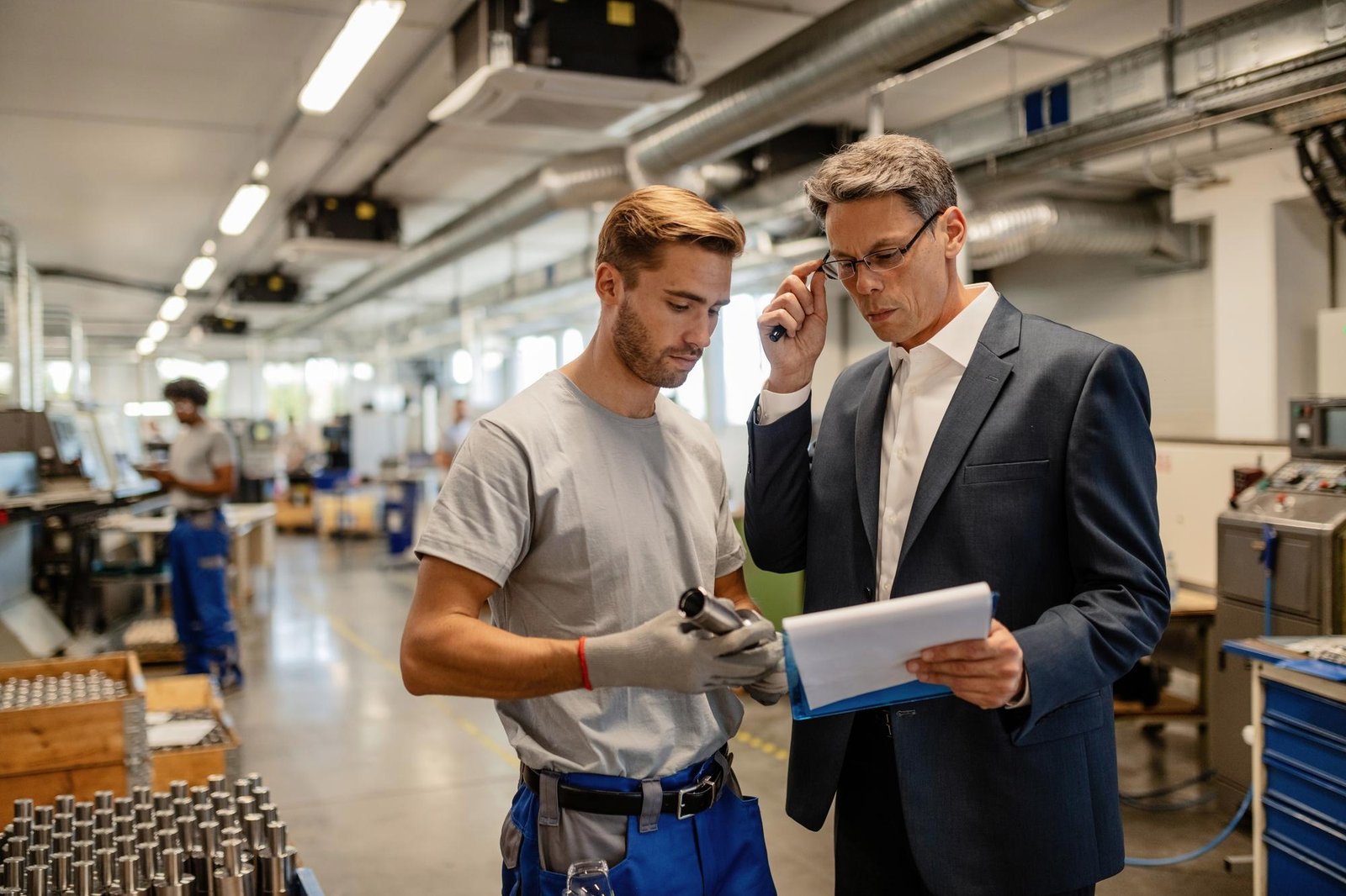 mid adult engineer young worker cooperating while analyzing reports steel factory